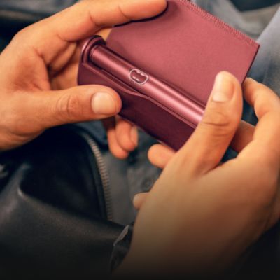 Person öffnet Case mit ILUMA i Tabakerhitzer in der Farbe Garnet Red.