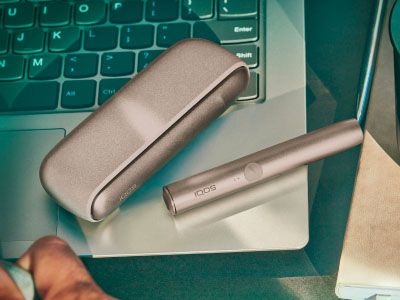 Une main montrant un appareil IQOS à une autre personne.