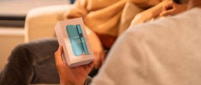 A person holding a box that contains a booklet on IQOS ILUMA.