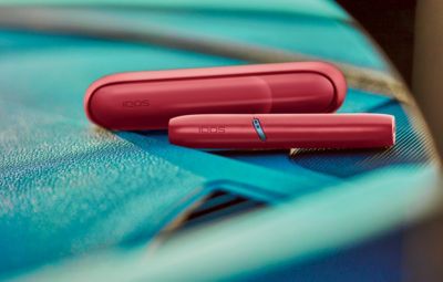 Appareil IQOS rouge scarlet posé sur une surface bleue