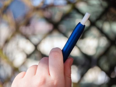 A person holding an IQOS device in hand.