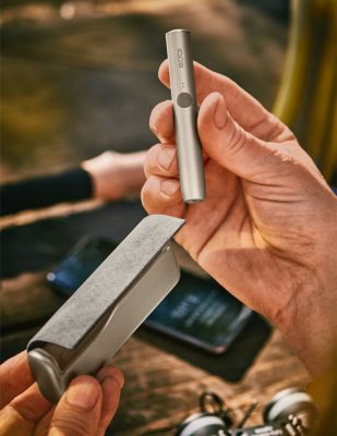 A person holding an IQOS ILUMA PRIME Holder.