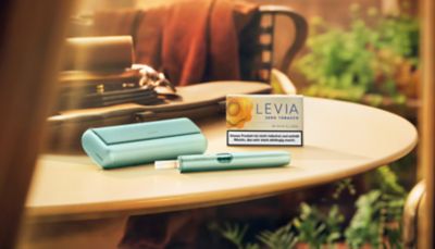 LEVIA Nikotinsticks und Tabakerhitzer IQOS ILUMA i liegen auf einem Tisch.