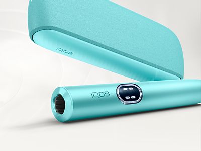 Держатель IQOS ILUMA i цвета Лазурный бриз перед зарядным устройством на сером фоне