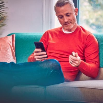 Man working at laptop, one hand on IQOS device on table