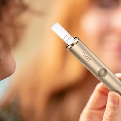 Jemand hält ein IQOS ILUMA Device mit eingesetztem TEREA Tabakstick in der Hand