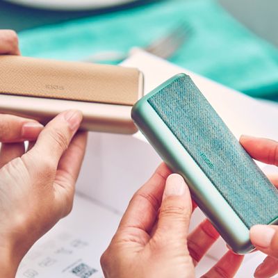 Zwei Personen halten zwei IQOS ILUMA Geräte in der Hand