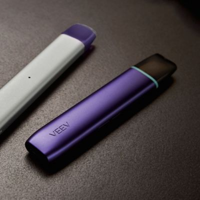 Ein VEEV ONE und ein VEEV NOW Device liegen auf einer schwarzen Oberfläche