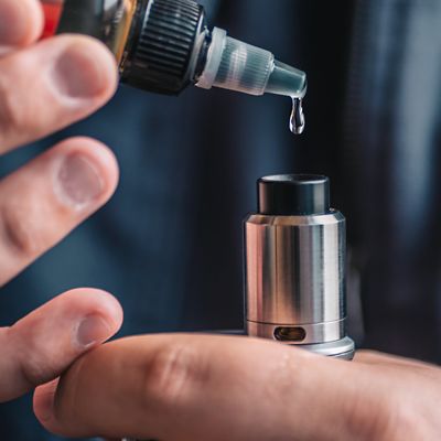 Nahaufnahme von einer Hand, die ein E-Liquid bei einer elektronischen Zigarette auffüllt