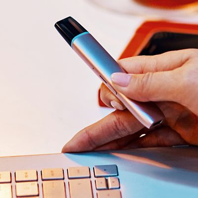 Nahaufnahme von einem VEEV ONE Device in Silky Grey neben einem Notebook