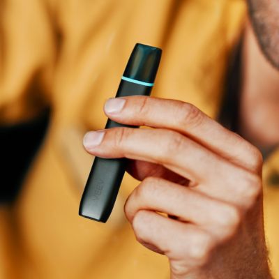 Jemand in einem gelben Pullover hält ein VEEV ONE Device in Velvet Black in der Hand