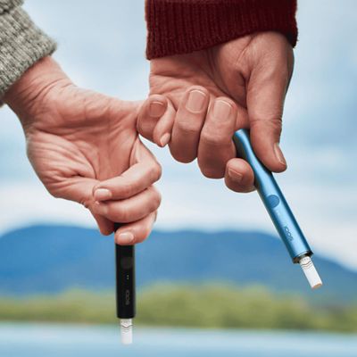 Zwei Hände halten jeweils ein IQOS ILUMA Device