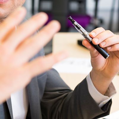 Eine Person im Anzug hält eine E-Zigarette in der Hand