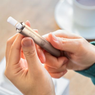 IQOS ILUMA Holder inkl. TEREA Stick in den Händen einer Frau