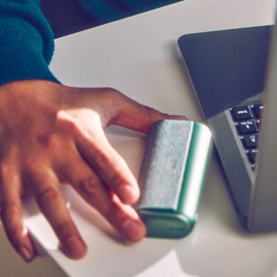 Mann im Anzug mit Handy in der Hand vor einem Laptop