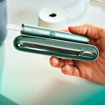 IQOS ILUMA Prime neben einem Laptop