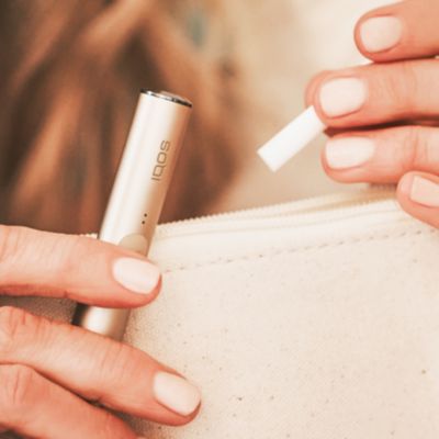 Jemand hält ein IQOS ILUMA Device und einen TEREA Tabakstick in den Händen