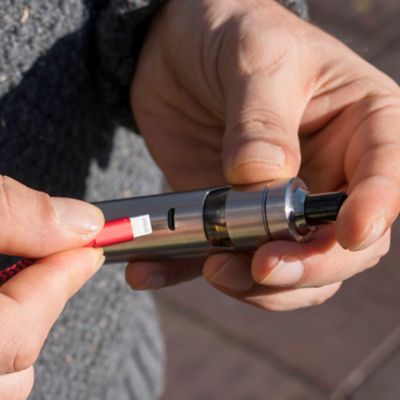 Jemand steckt ein USB-C-Ladekabel in eine E-Zigarette