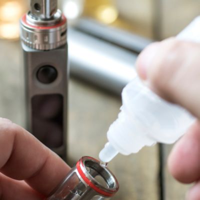 Jemand füllt Liquid in eine E-Zigarette nach