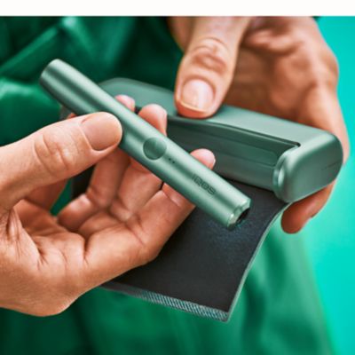 Jemand entnimmt ein IQOS ILUMA PRIME in Moss Green aus dem Pocketcharger