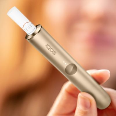 Jemand hält ein IQOS ILUMA Device mit eingesetztem TEREA Tabakstick in der Hand