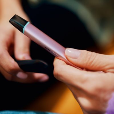 Jemand hält ein VEEV ONE mit eingesetztem Pod in der Hand