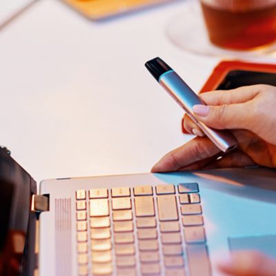 Frau hält VEEV Gerät vor Laptop