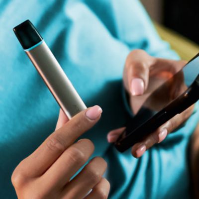 Frau hält VEEV ONE Gerät und Mobiltelefon