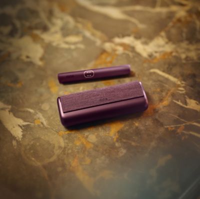 IQOS Iluma i Prime morado y verde sobre superficie de mármol.
