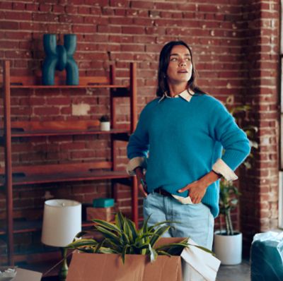 Mujer en ventana sosteniendo un IQOS Iluma i ONE azul.