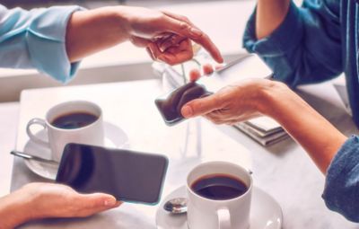 A happy girl with a red IQOS in her hands hugs a guy.
