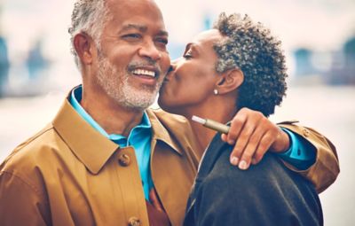 A man holding an IQOS device embraces his partner.