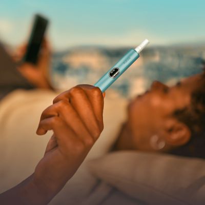 Zwei IQOS ILUMA Geräte liegen nebeneinander auf einem roten Tisch