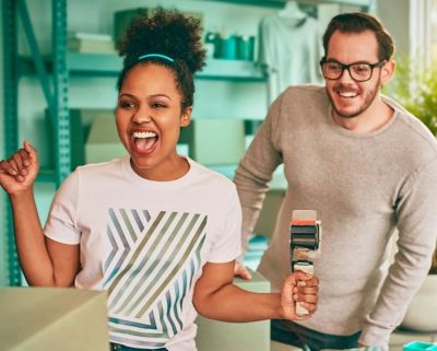 A man driving a car and a woman sitting in the passenger seat holding an IQOS device.