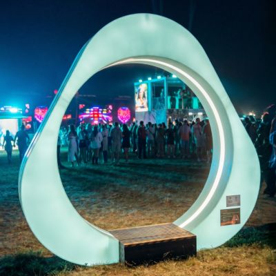Osvetlená oblúková inštalácia v tvare IQOS loga stojí na trávnatej ploche