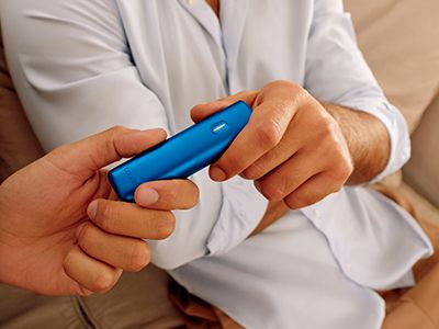 Une personne passe un appareil BONDS by IQOS à son ami.