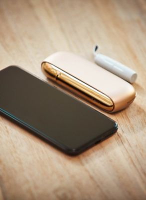 A mobile and a gold IQOS on a table
