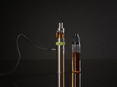 Vape device placed beside an e-liquid bottle