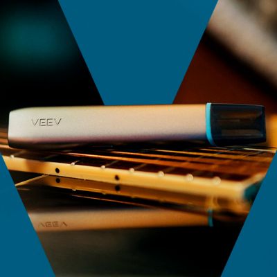 Ecig VEEV ONE rose posée sur une surface dorée