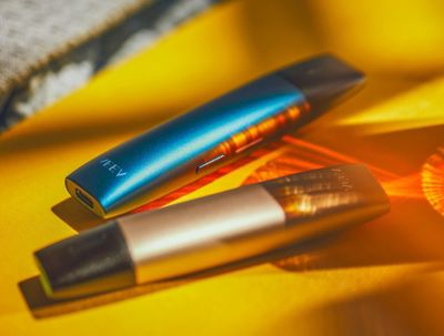 Dvě IQOS VEEV zařízení na žlutém ubruse