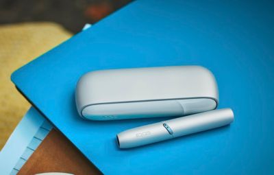 Appareil IQOS gris posé sur un carnet bleu