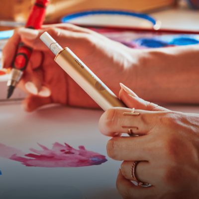 Jemand, der zeichnet, hält ein IQOS ILUMA in der Hand