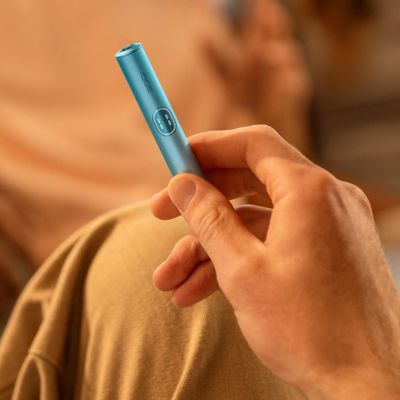 A person with a Jade Green IQOS ILUMA PRIME Holder and Pocket Charger in a full wrap.