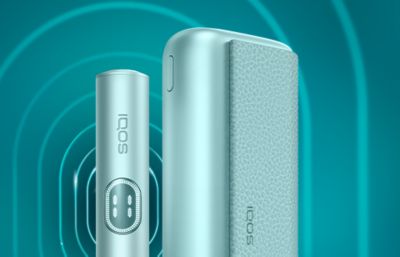 IQOS ILUMA i PRIME device and charger on turqoise background