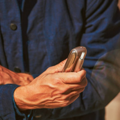 A gold IQOS device in a person's hand.