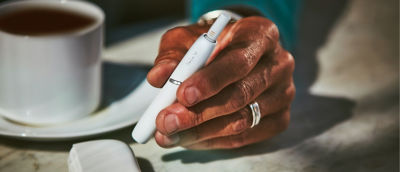 A  hand holding a white IQOS device.