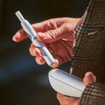 A while IQOS device in a person's hand.