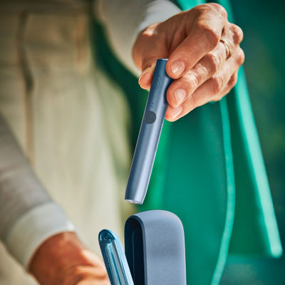 An architect takes a mid azure blue ILUMA device from its charger.