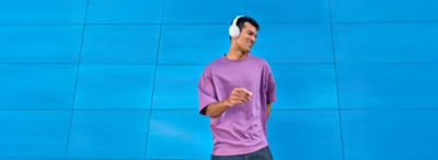 Homme portant une chemise violette claire, écoutant de la musique et dansant